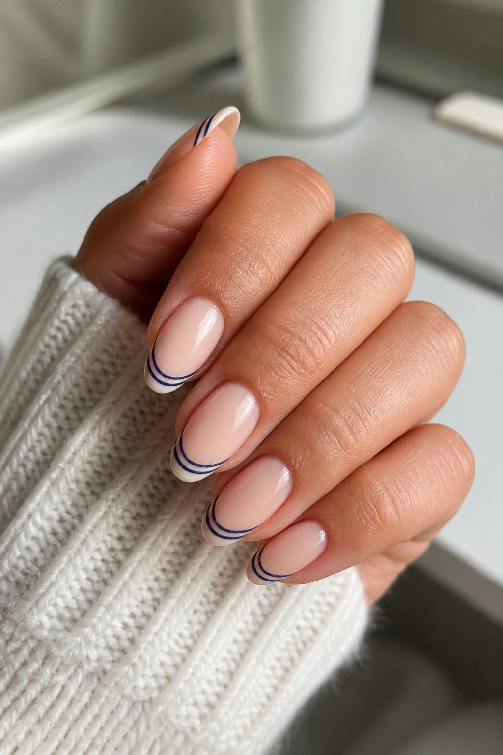 Almond nails with navy and white stripes on tips over nude base
