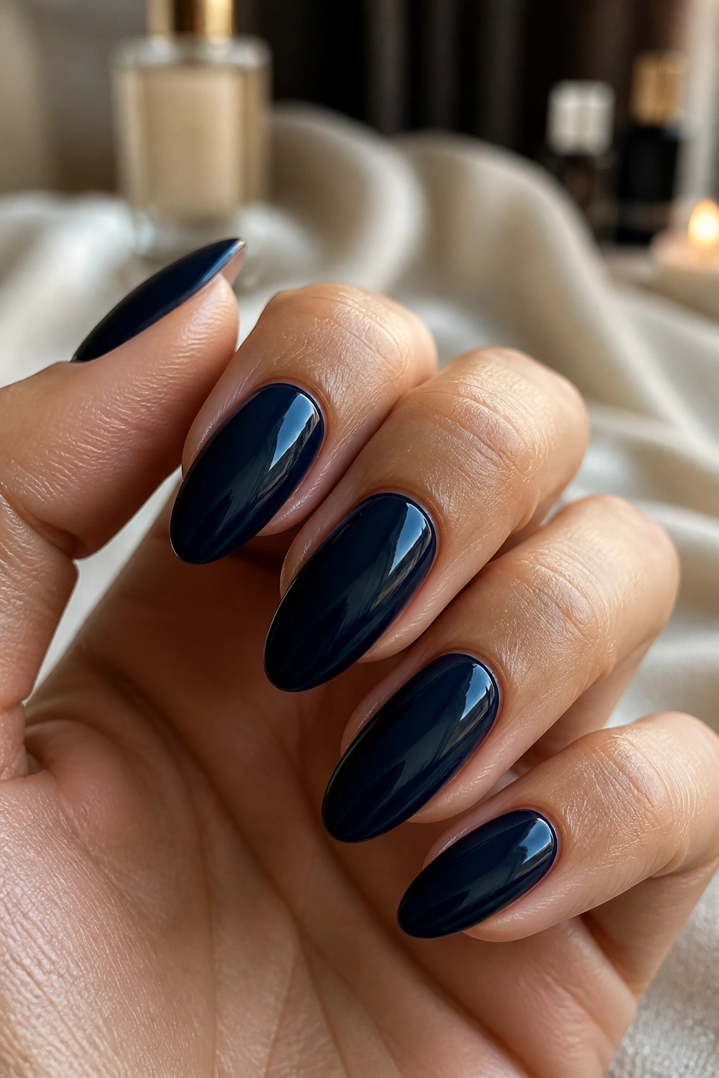 Close-up of glossy navy almond nails with a tiny cuticle gap on a real hand