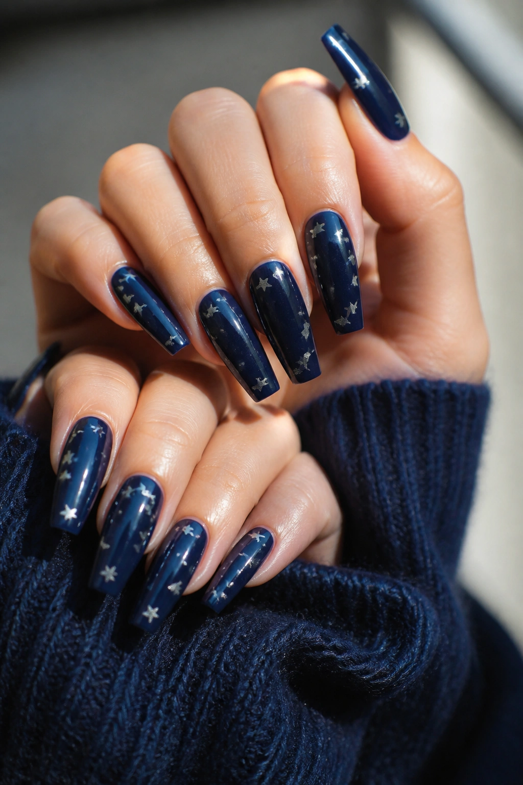 Close-up of navy coffin nails with silver stars on a real person's hands in natural light