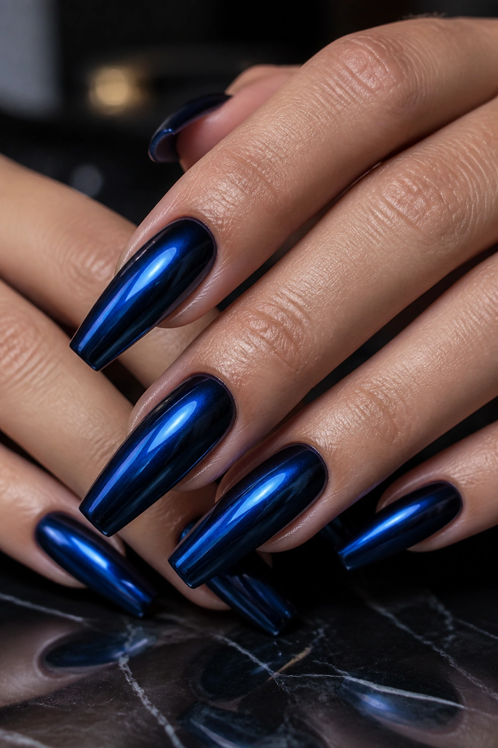 Close-up of deep navy chrome nails over black base showing blue reflection.