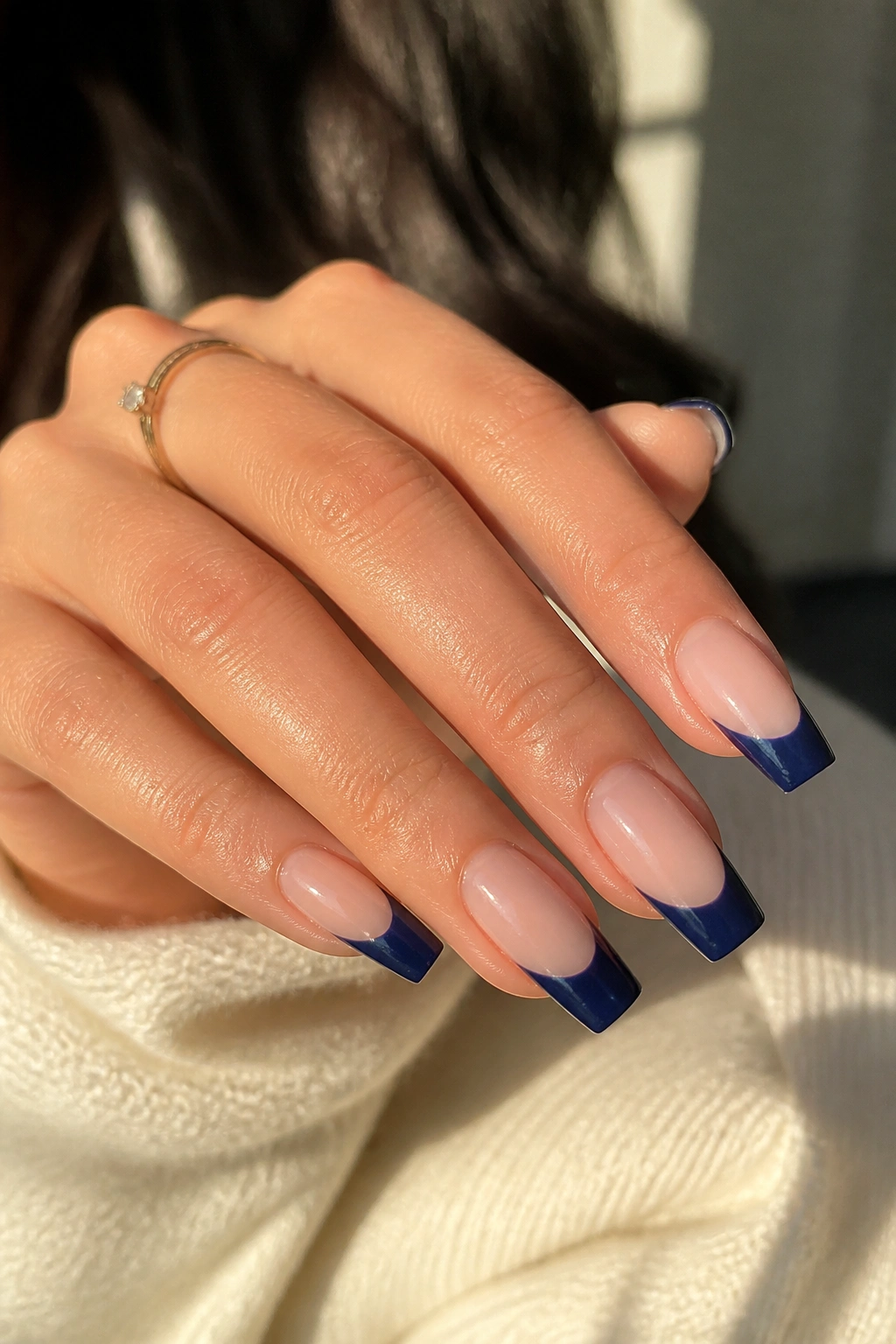 Close-up of a real hand with navy French coffin nails on nude base