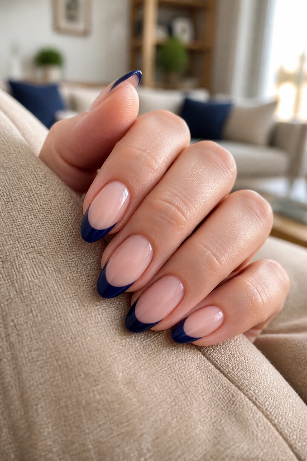 Close-up of almond nails with navy French tips on nude base