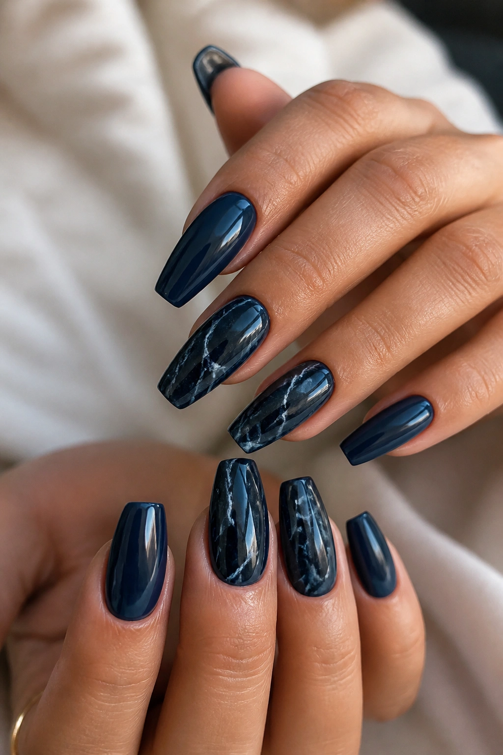 Close-up of navy marble nails with white veining on accent fingers