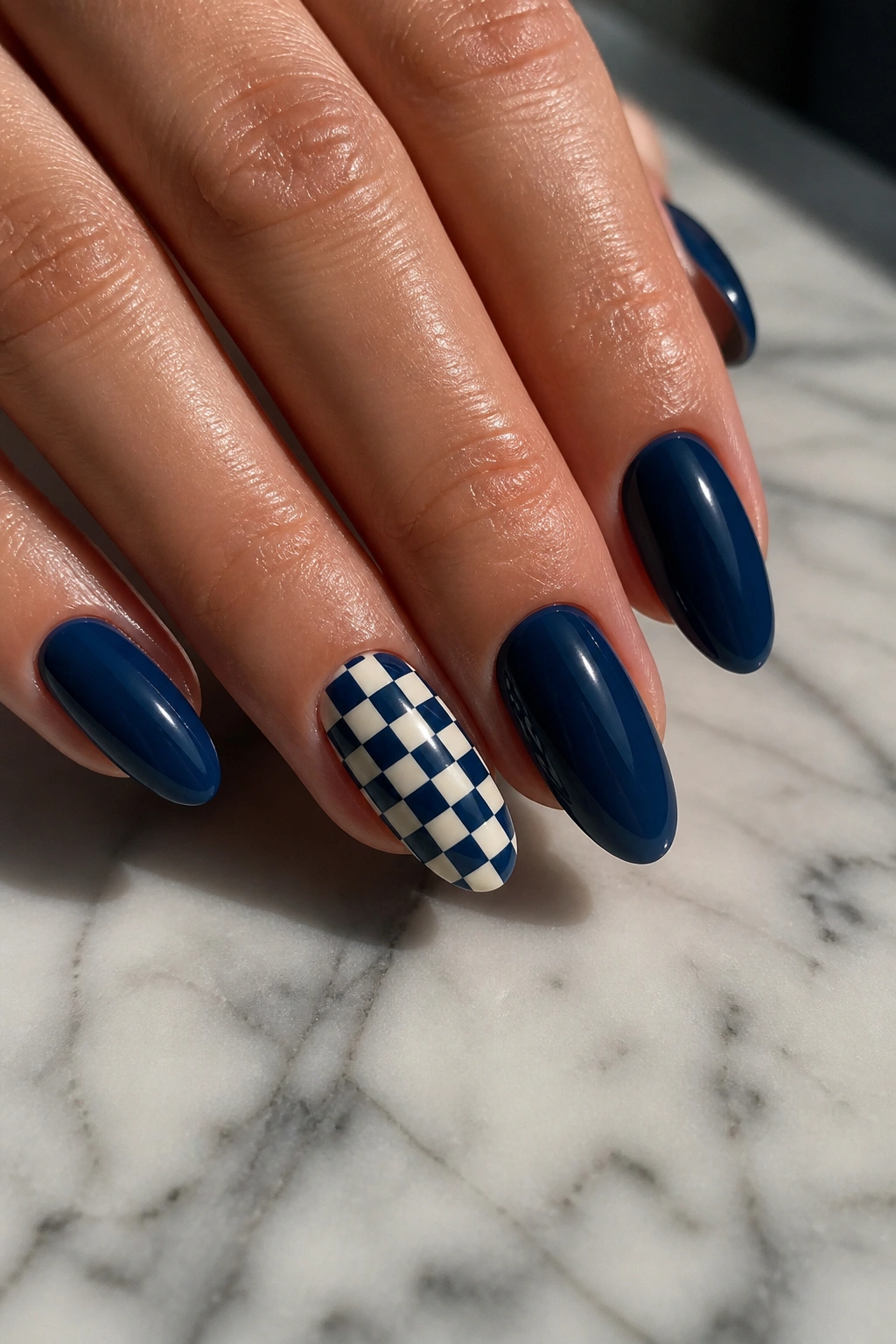 Almond nails with navy base and checkerboard accent nail