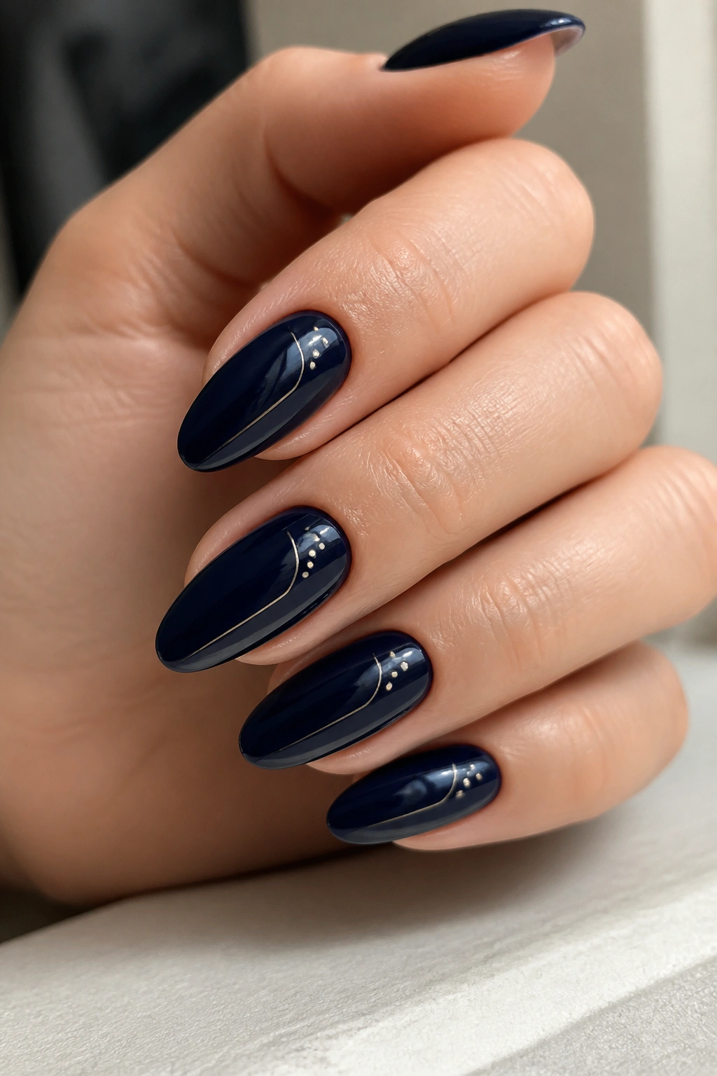 Close-up of navy almond nails with micro dots and fine lines on a real hand