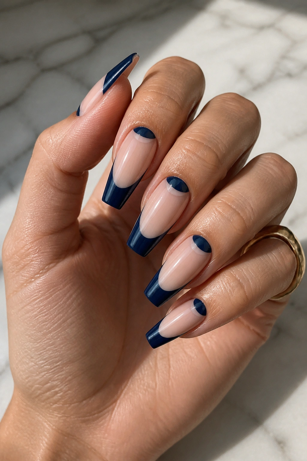 Navy French tips with negative-space half moons on coffin nails