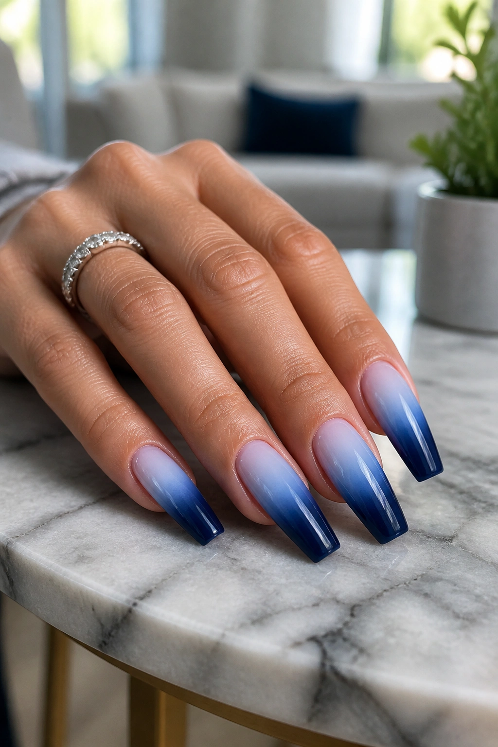 Close-up of navy to sky blue ombre nails on a real hand in a sunny room