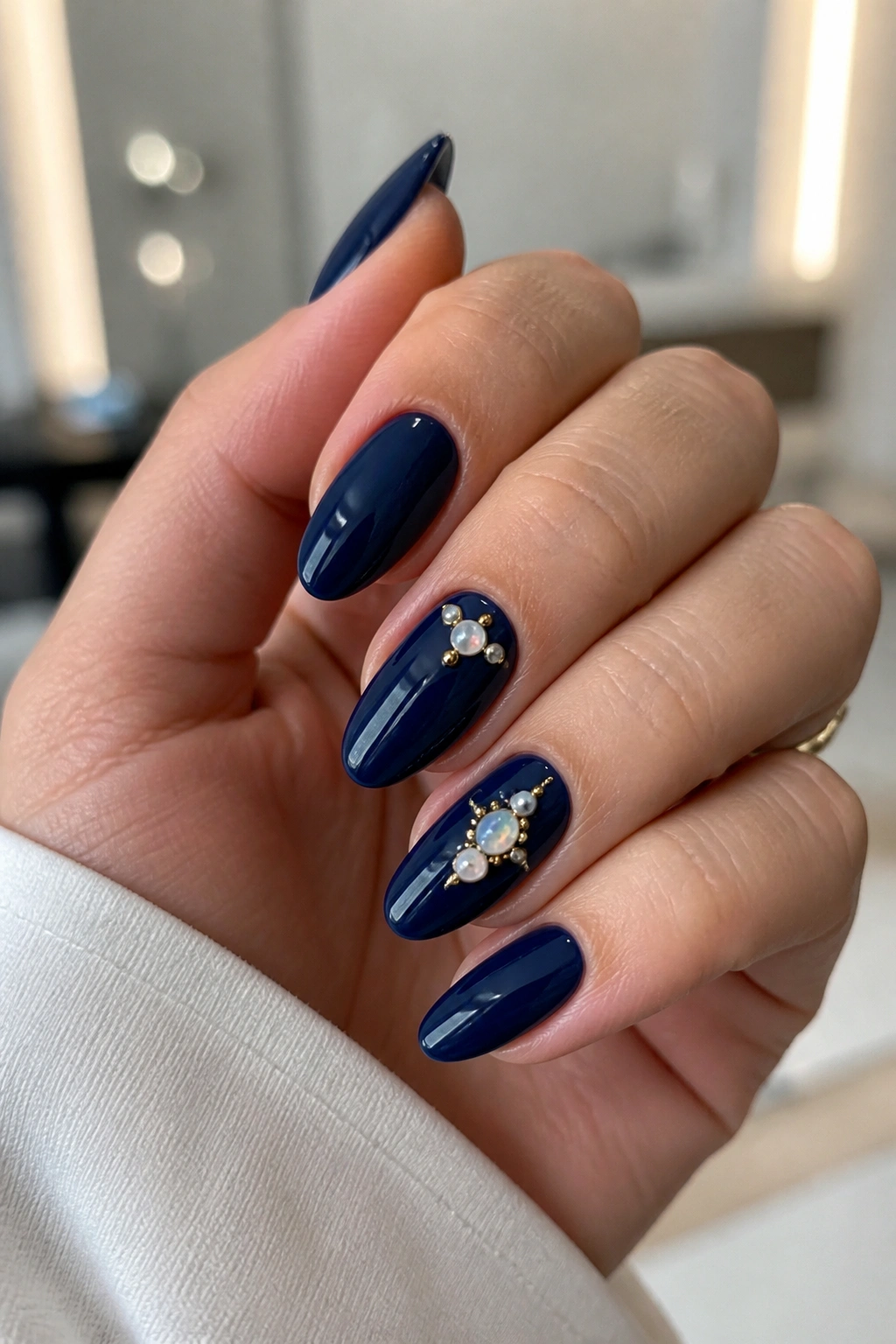 Navy nails featuring pearl and opal accents on a real hand