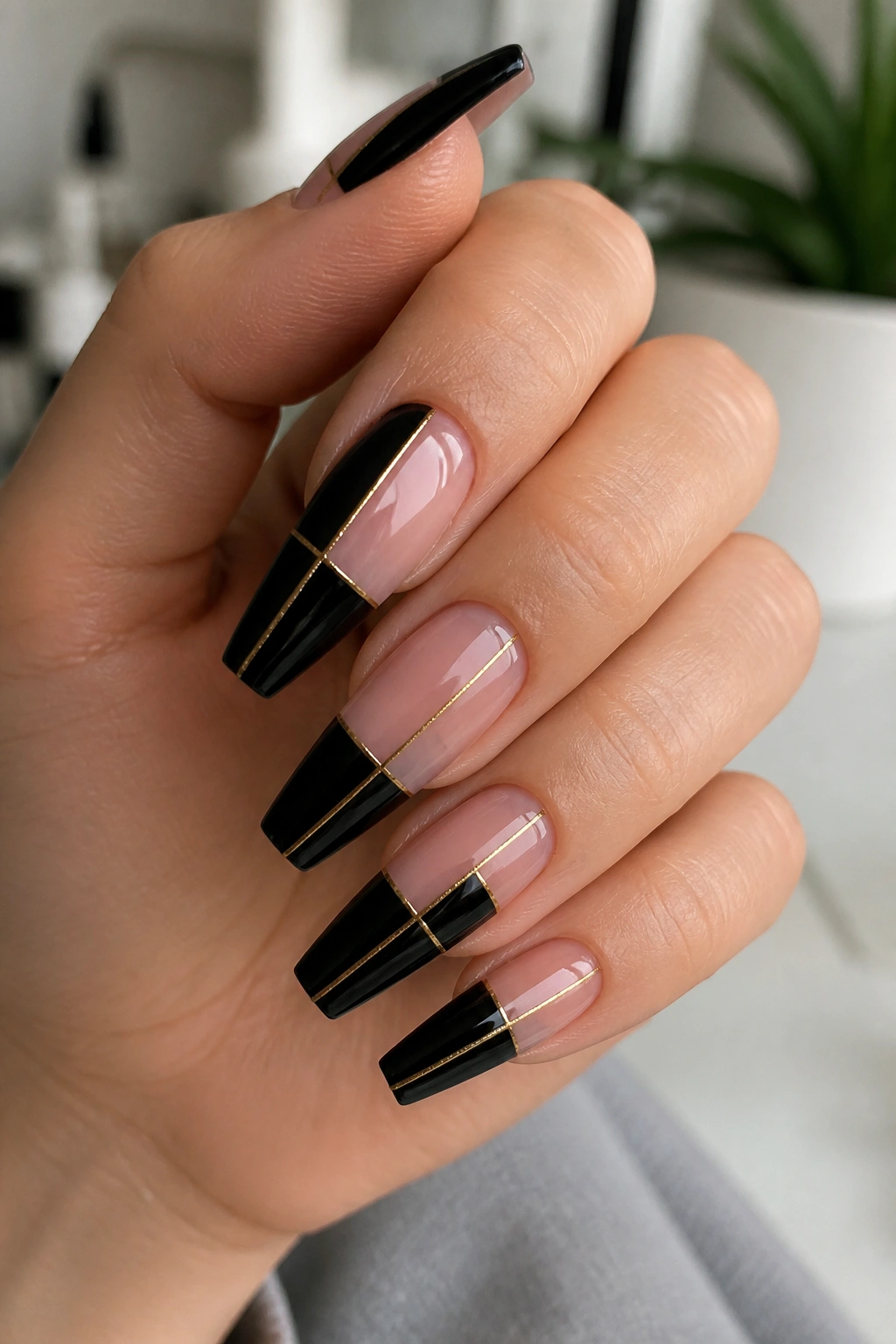 Close-up of negative-space coffin nails with nude blocks and gold wire