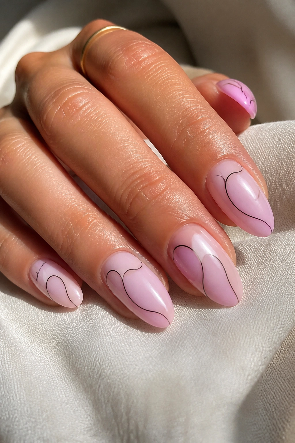 Close-up of almond nails with light-pink base and negative-space line art on a real hand