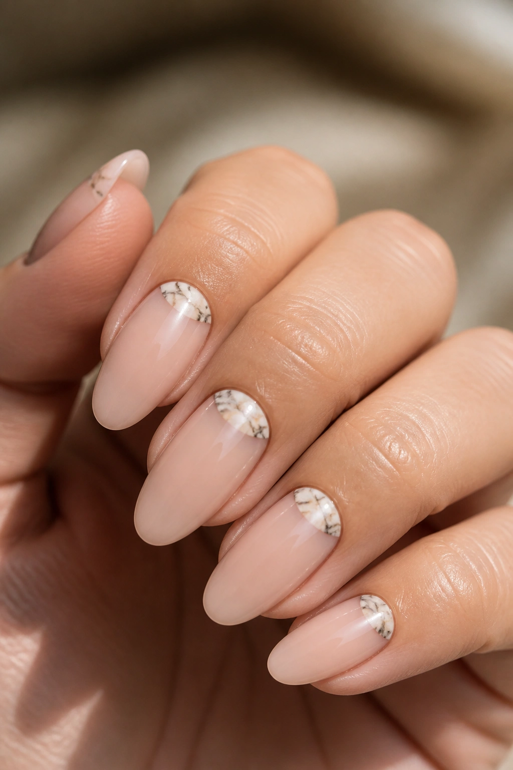 Close-up of almond nails showing negative space marble half-moons near cuticle