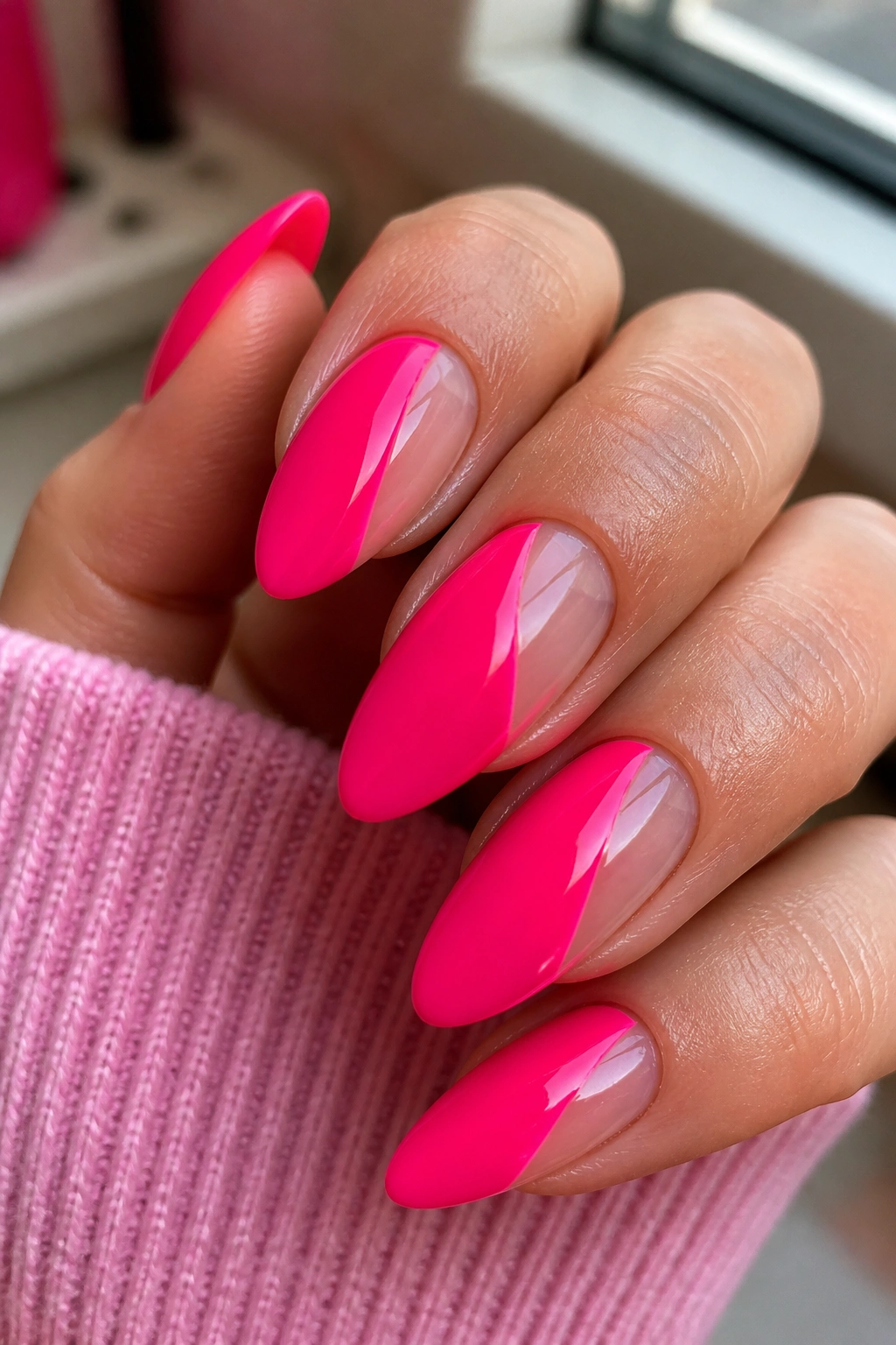 Close-up of negative-space hot pink almond nails on a real hand