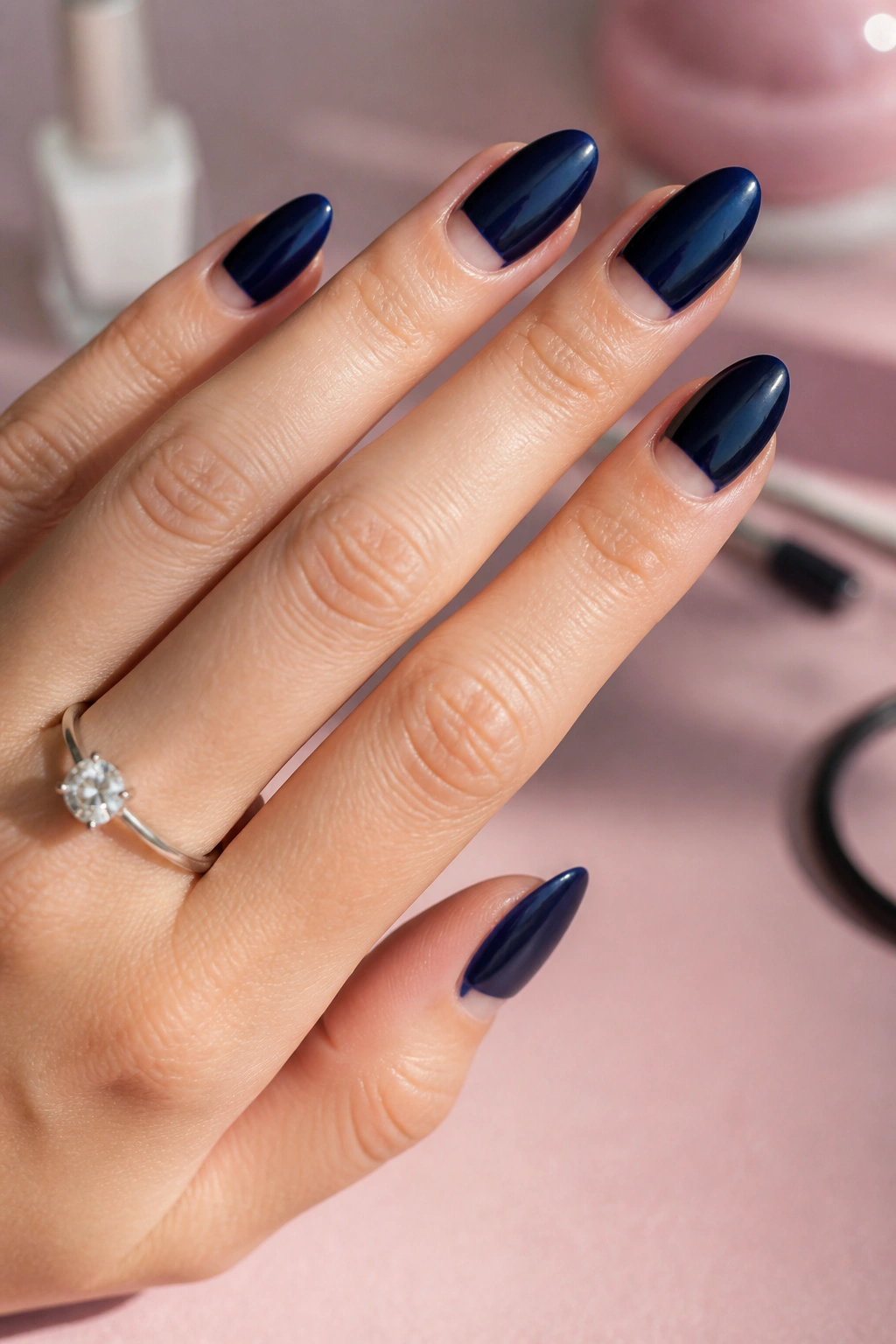 Navy nails with a negative-space half-moon near the cuticle on a real hand