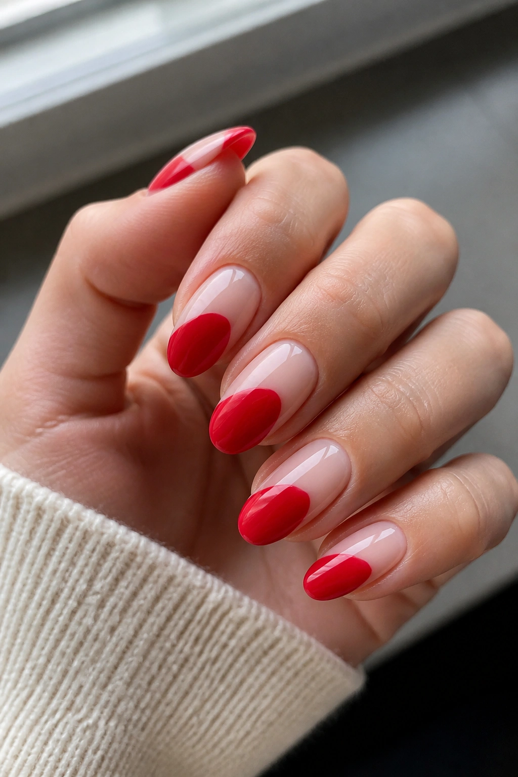 Close-up of nails with nude base and red negative-space on almond nails.