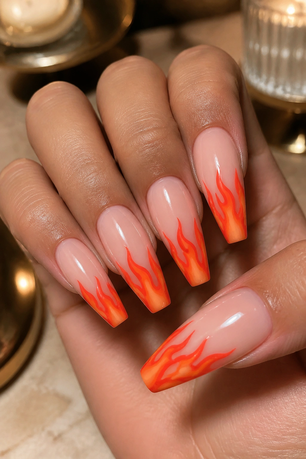 Close-up of red-orange flame nail art on nude-based coffin nails