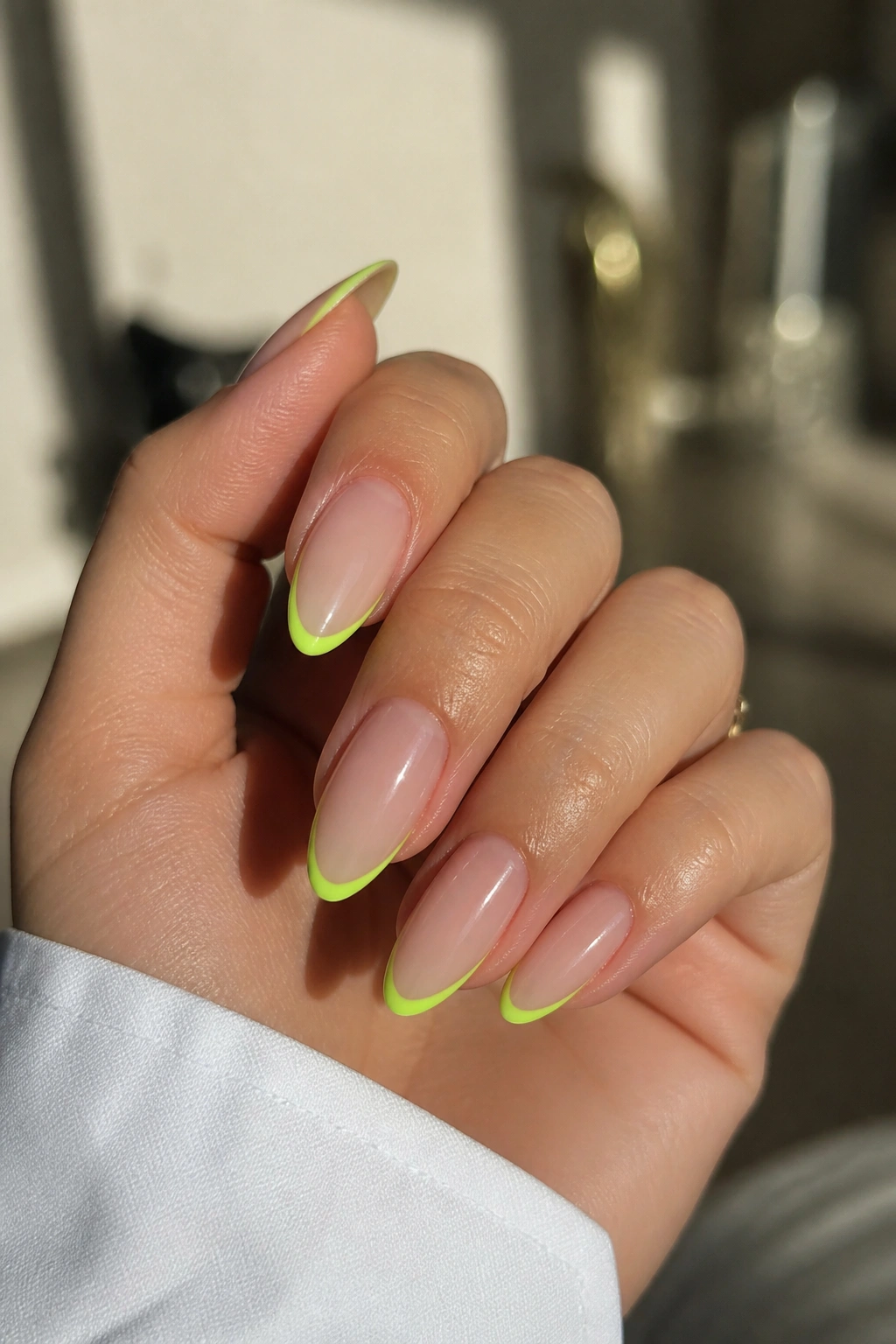 Close-up of real hand with almond nails showing neon lime micro-French on tips