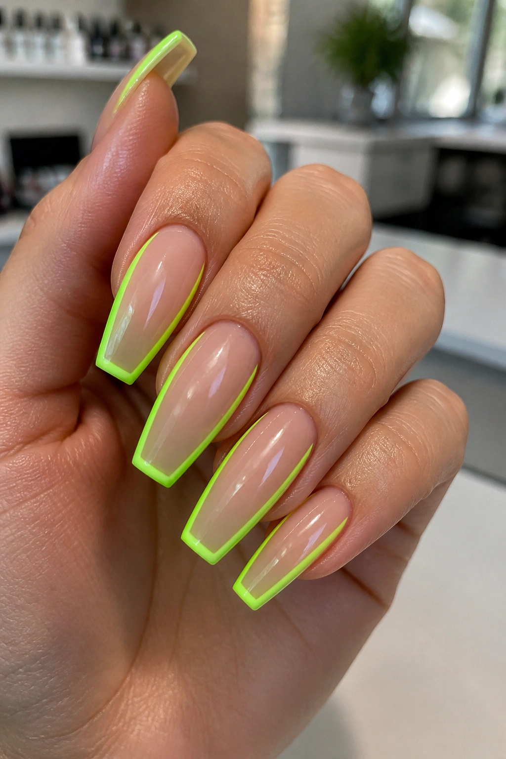 Close-up of neon outline coffin nails with lime green border on a real hand.