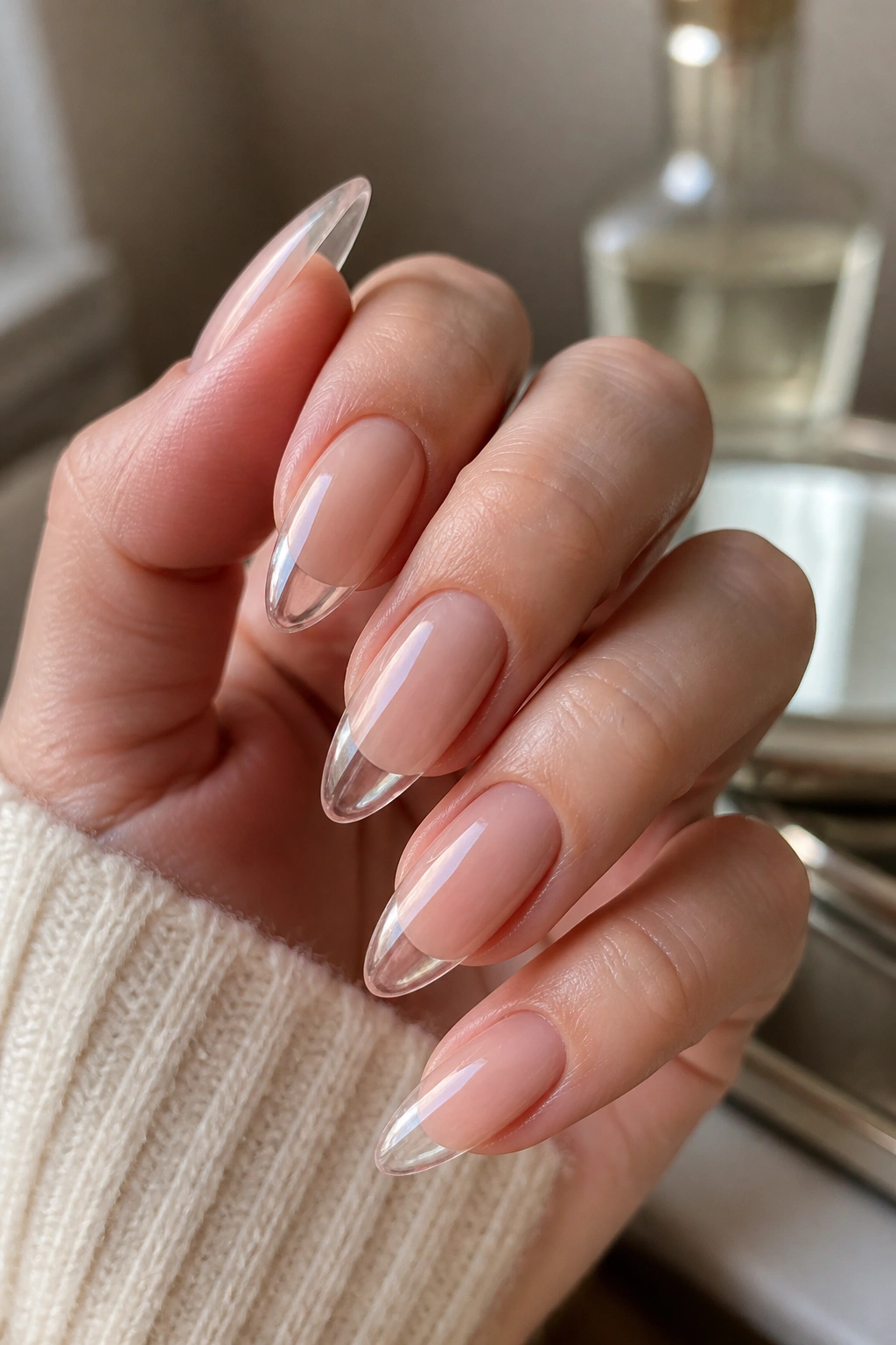 Close-up of hands with nude almond nails and clear-tip overlays