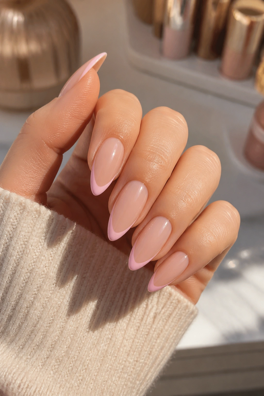 Close-up of a real hand with nude base almond nails and baby pink French tips