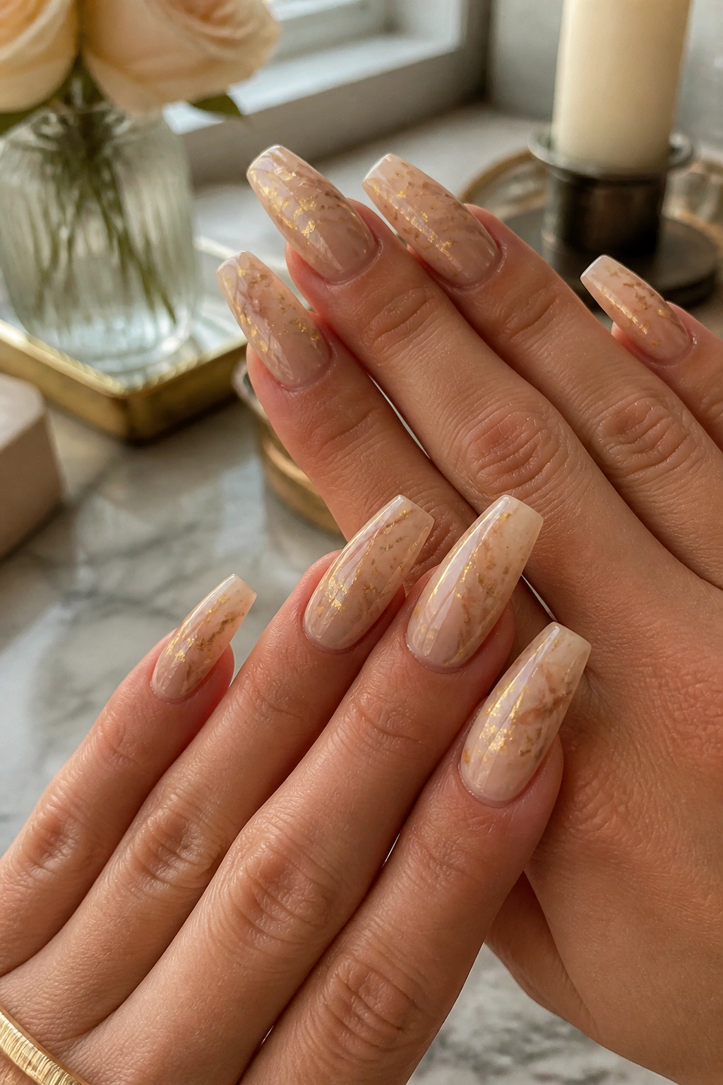 Nude beige marble nails with soft gold foil on real hands