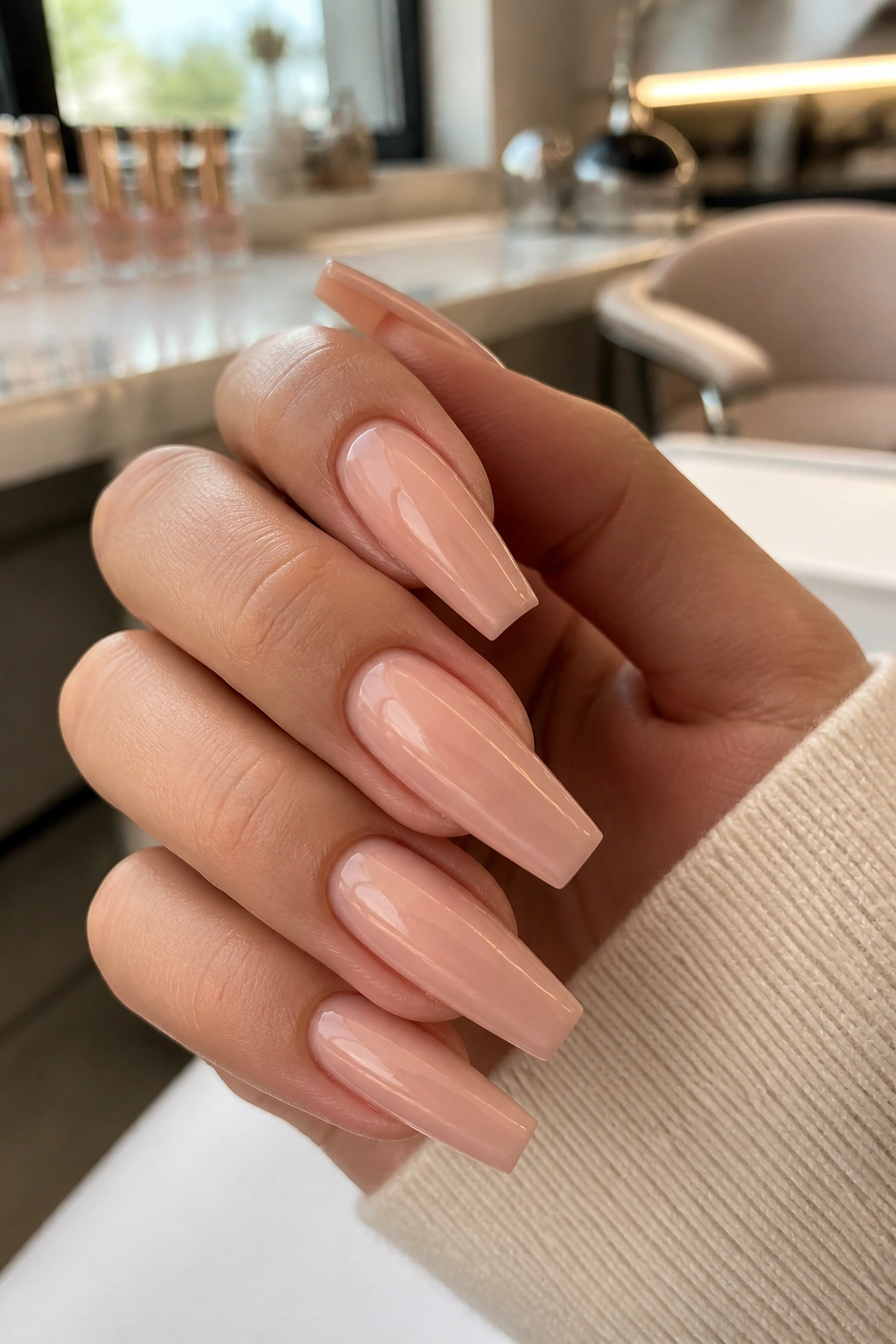 Close-up of a real hand with nude coffin nails, crisp shape and clean look