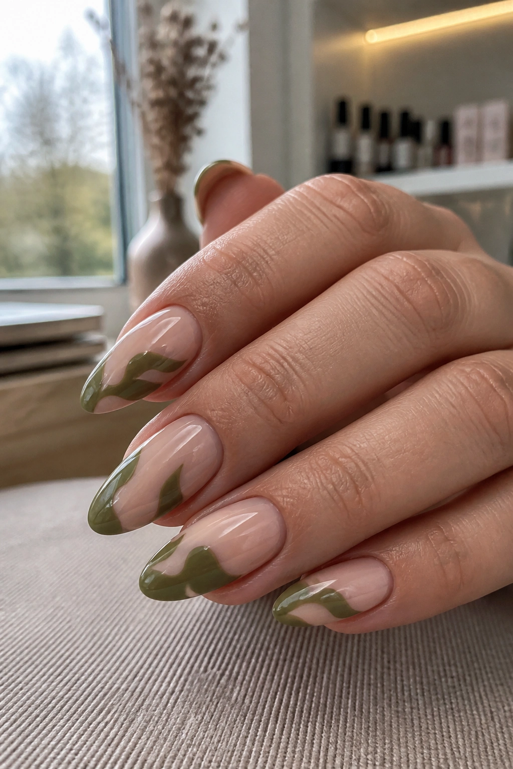 Close-up almond nails with olive negative-space design on a real hand