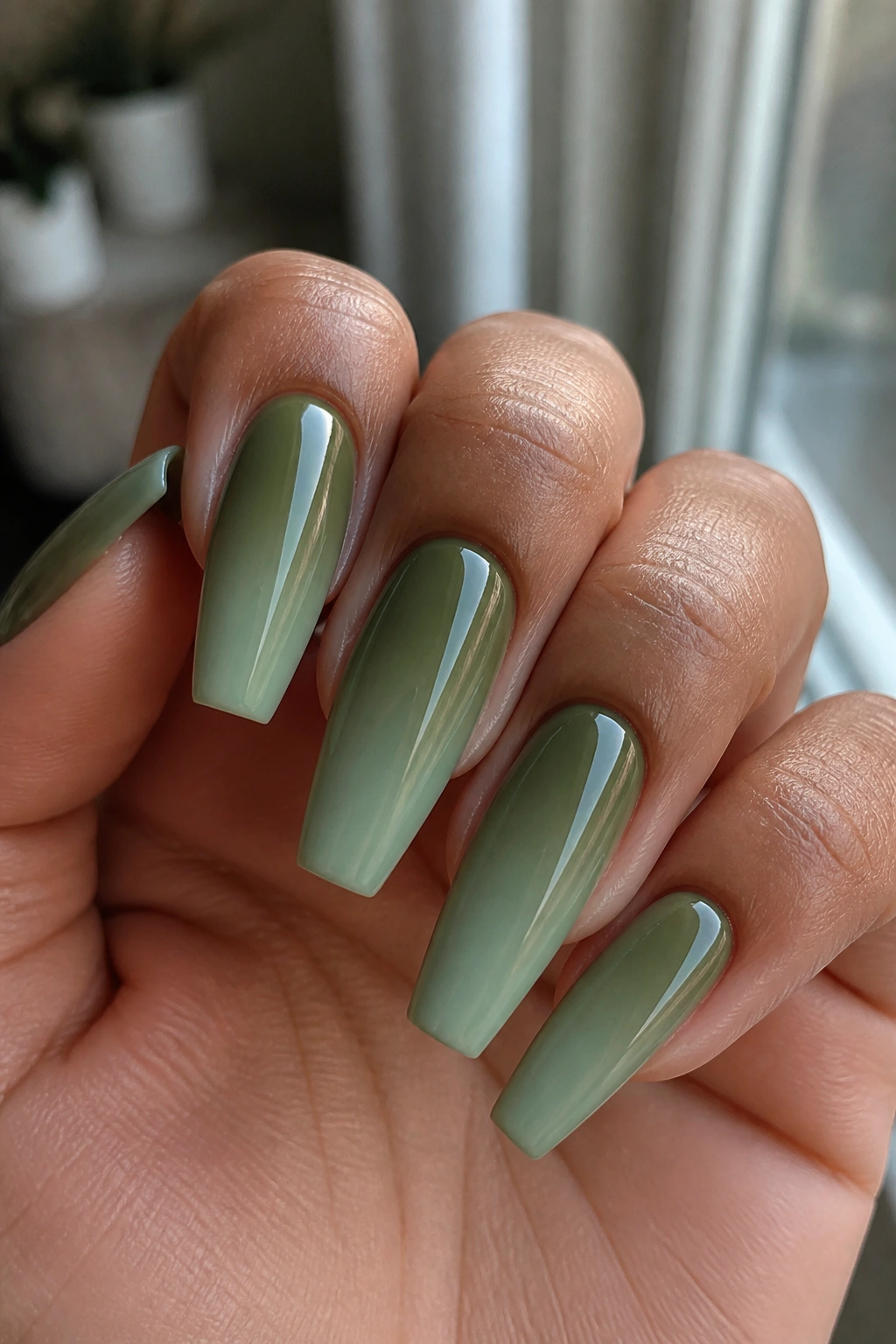 Close-up of hands with olive-to-sage ombré coffin nails