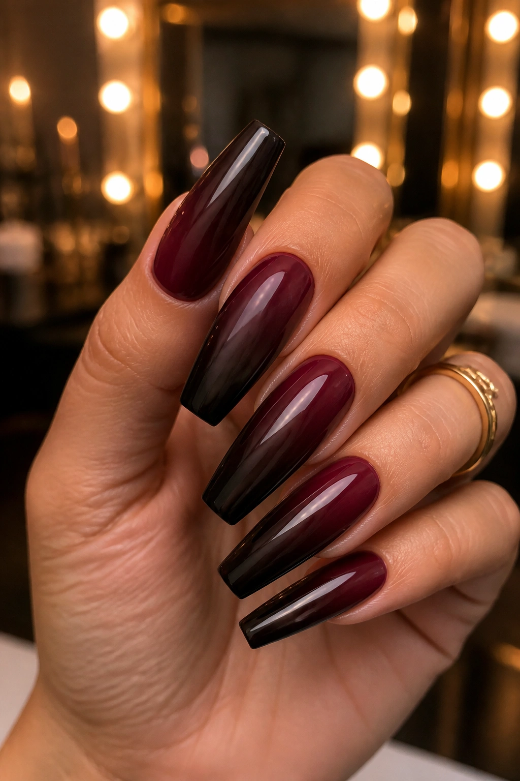 Close-up burgundy to espresso ombre coffin nails on a real hand