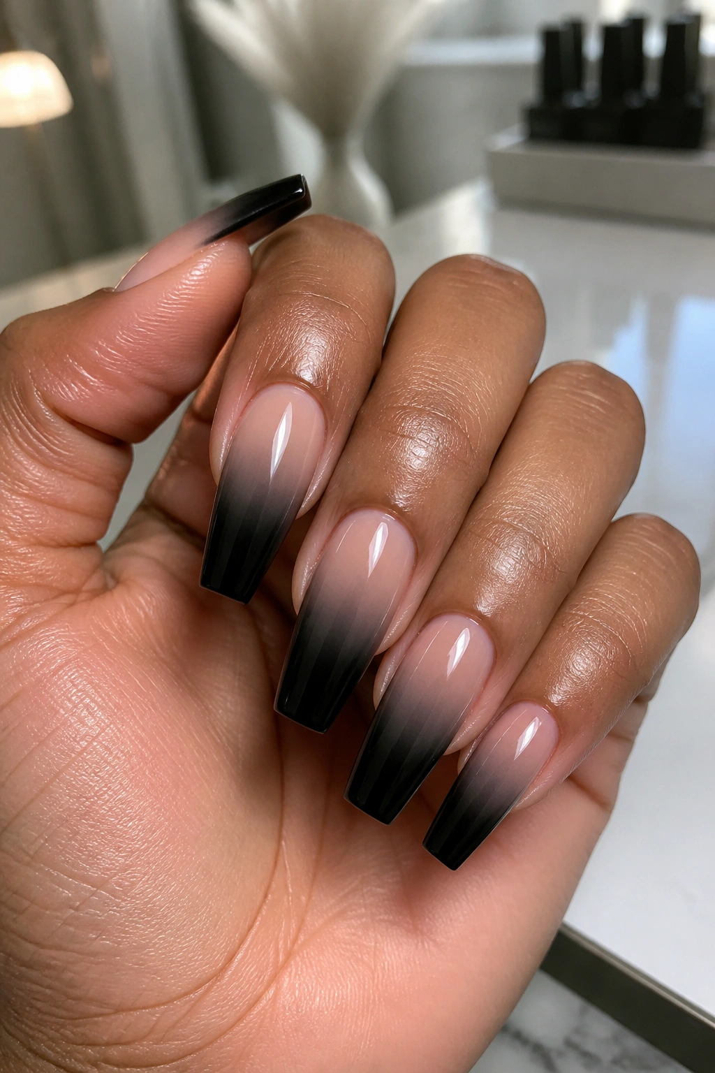 Close-up of nude-to-black ombre coffin nails on a real hand