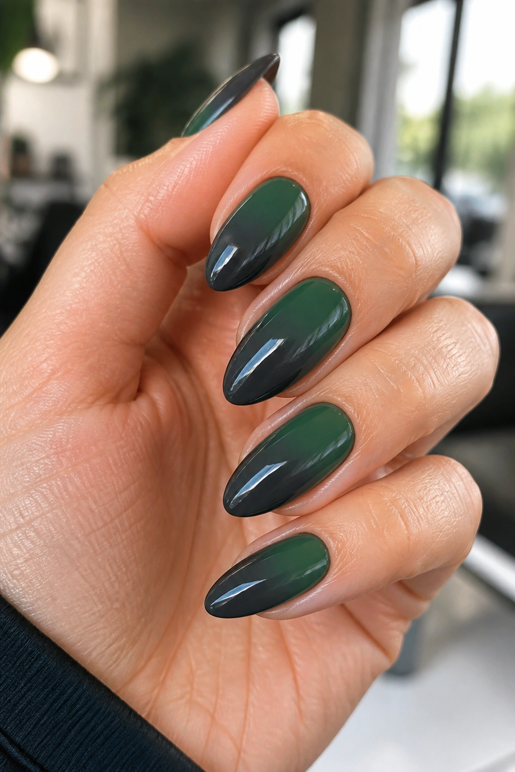 Close-up of charcoal-to-green ombré almond nails on a real hand with a smoky gradient
