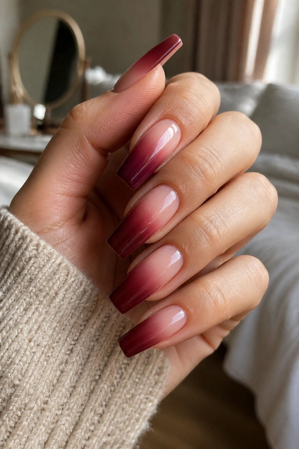 Close-up of hand with nude-to-wine ombre coffin nails