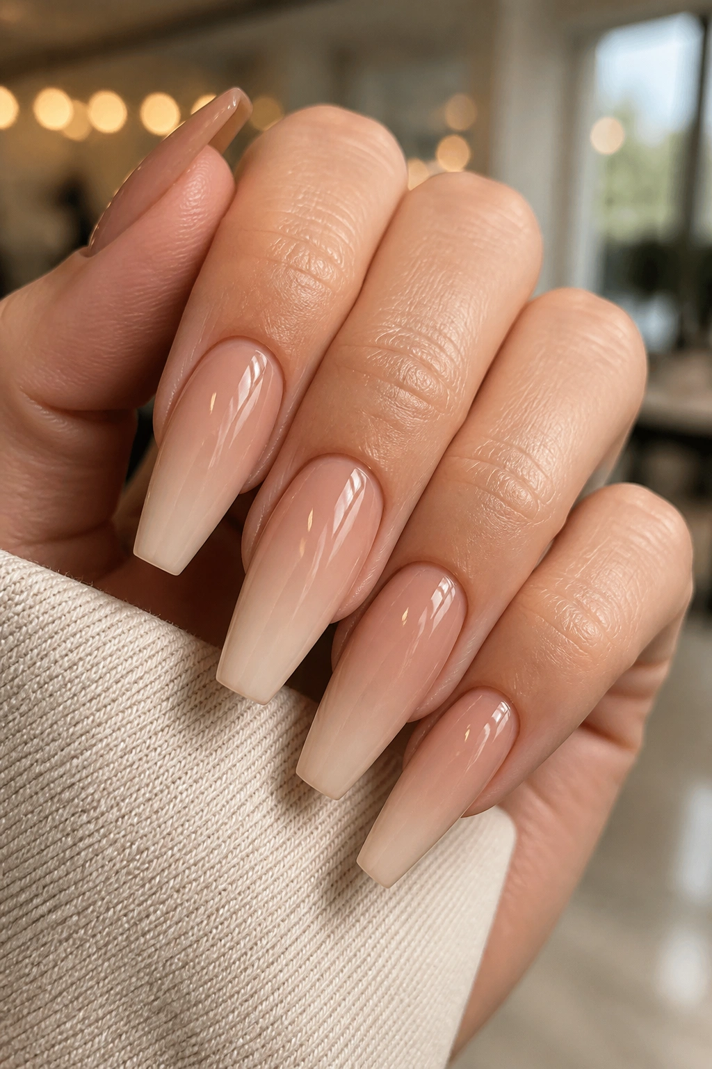Close-up of nude ombre coffin nails with a faded tip on real hand