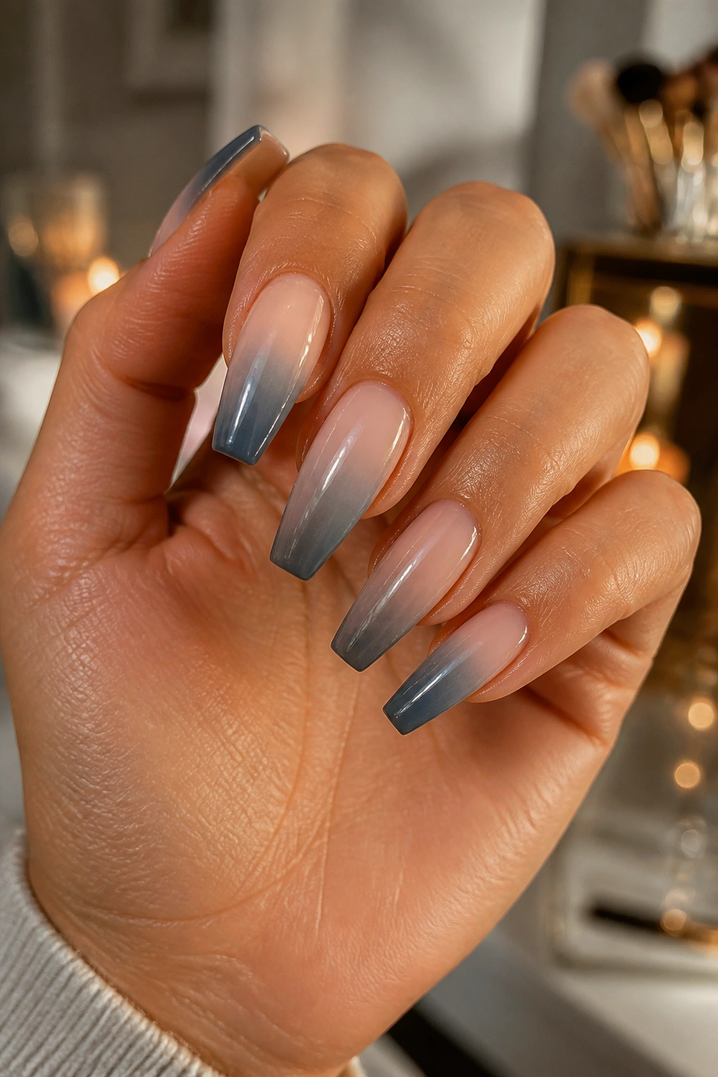Close-up of a real hand with smoky grey ombre coffin nails fading from nude to storm