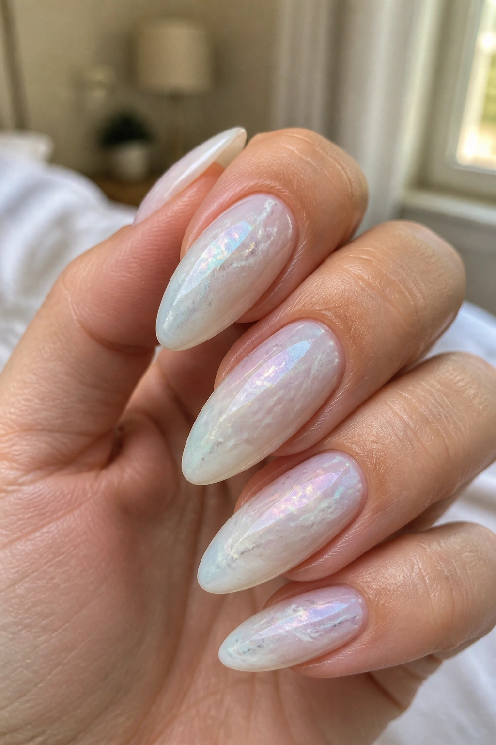 Close-up of almond nails with milky base and opalescent shimmer