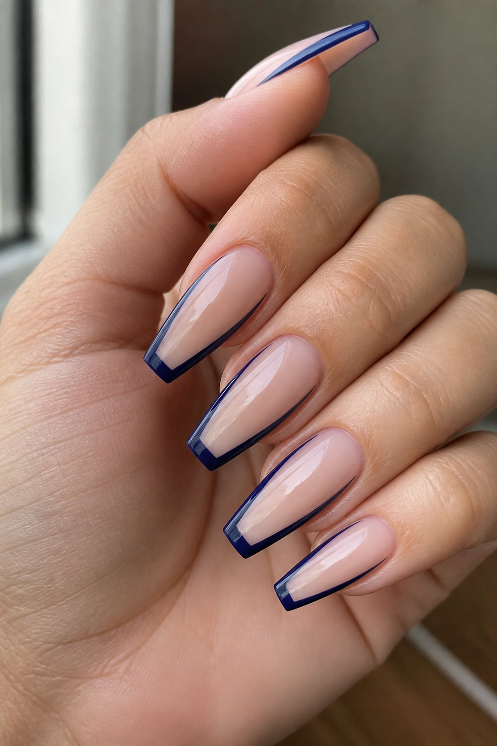 Close-up of dark blue outline coffin nails with sheer center on a real hand