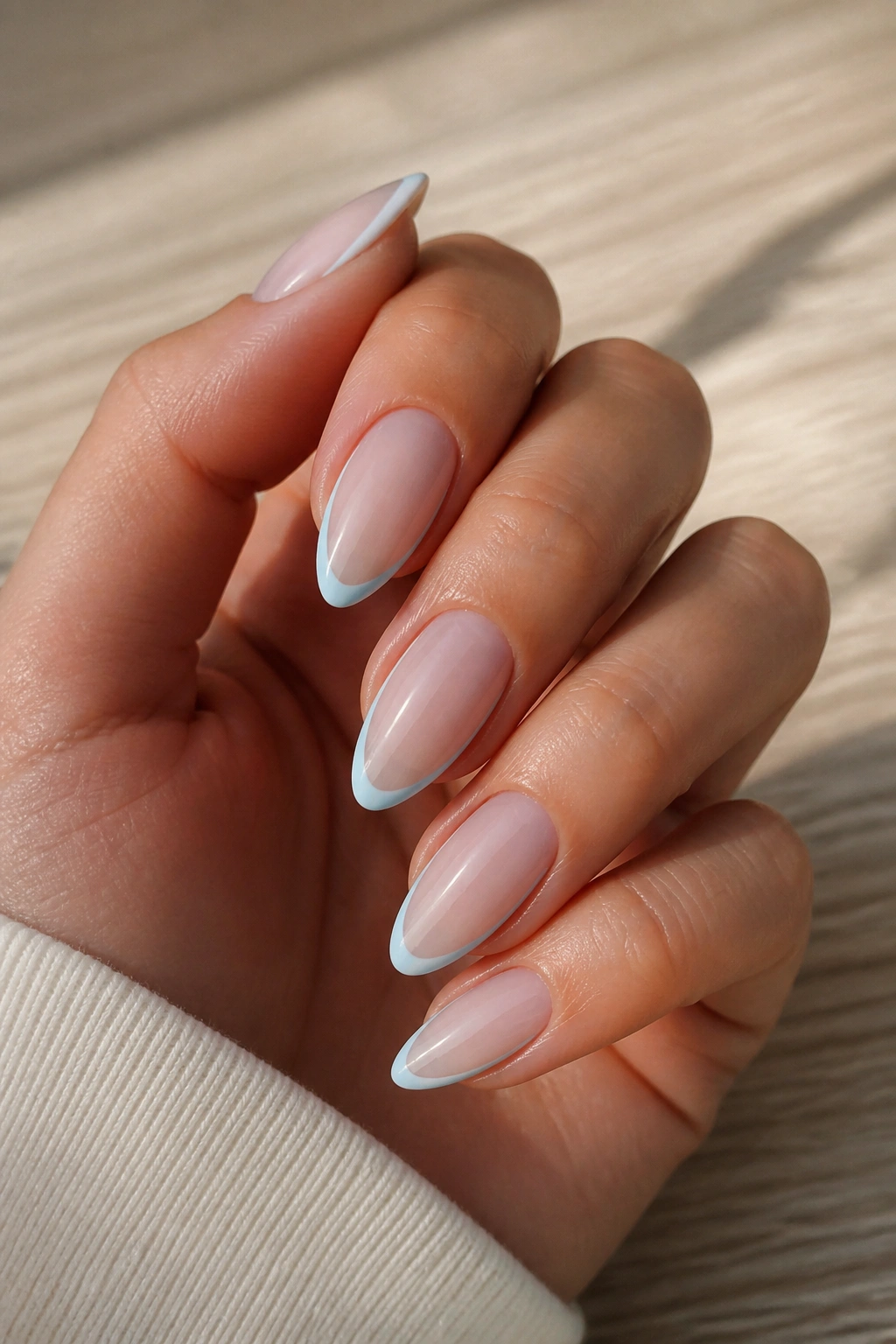 Nails with a thin blue outline on nude almond nails on real hand