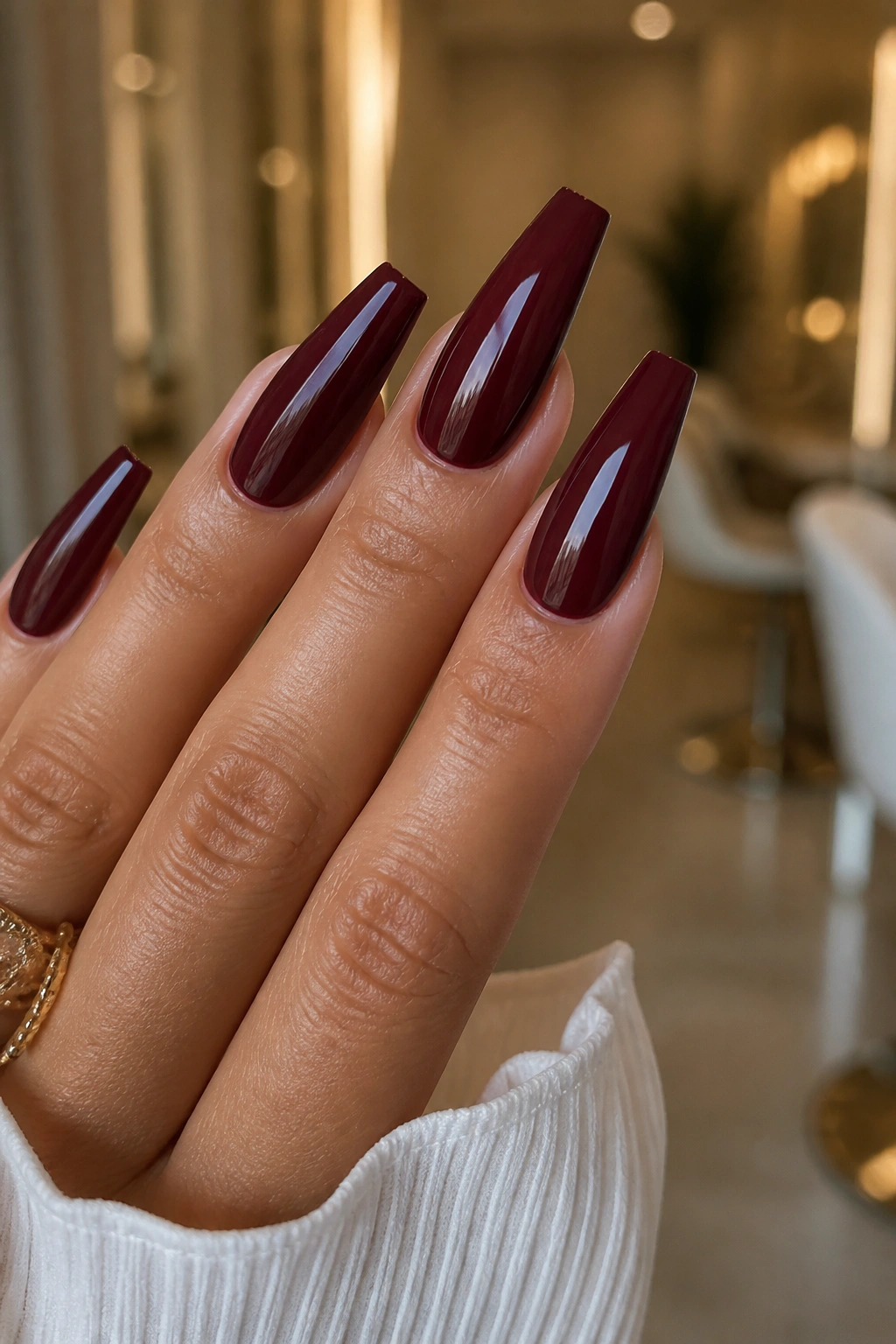 Close-up of glossy oxblood coffin nails with razor-clean edges on a real hand
