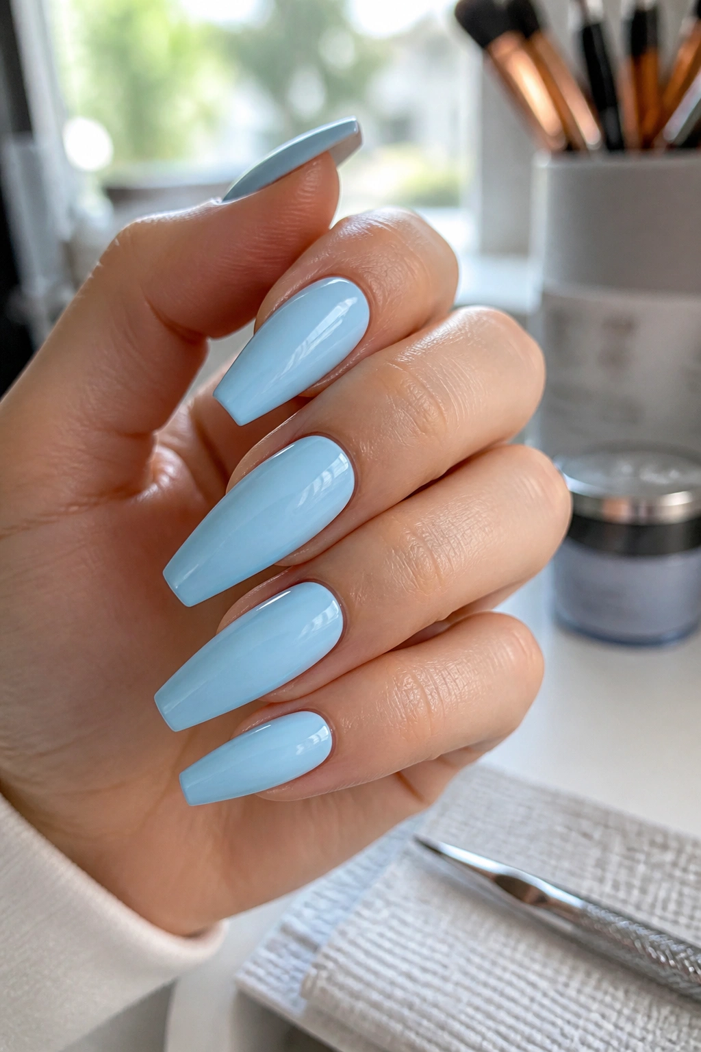 Close-up of pale blue coffin nails on a real hand at a clean salon station