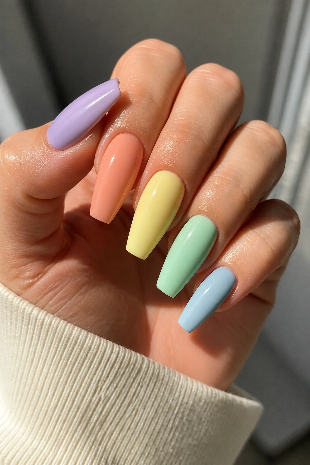 Close-up of real hand with milky pastel coffin nails in five colors