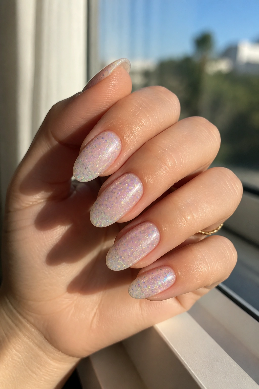 Almond nails with pastel rainbow glitter on a sheer base