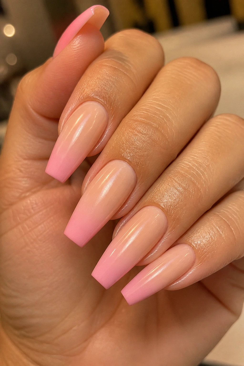 Close-up of peach-beige and pink coffin nails in a neutral fade on a real hand