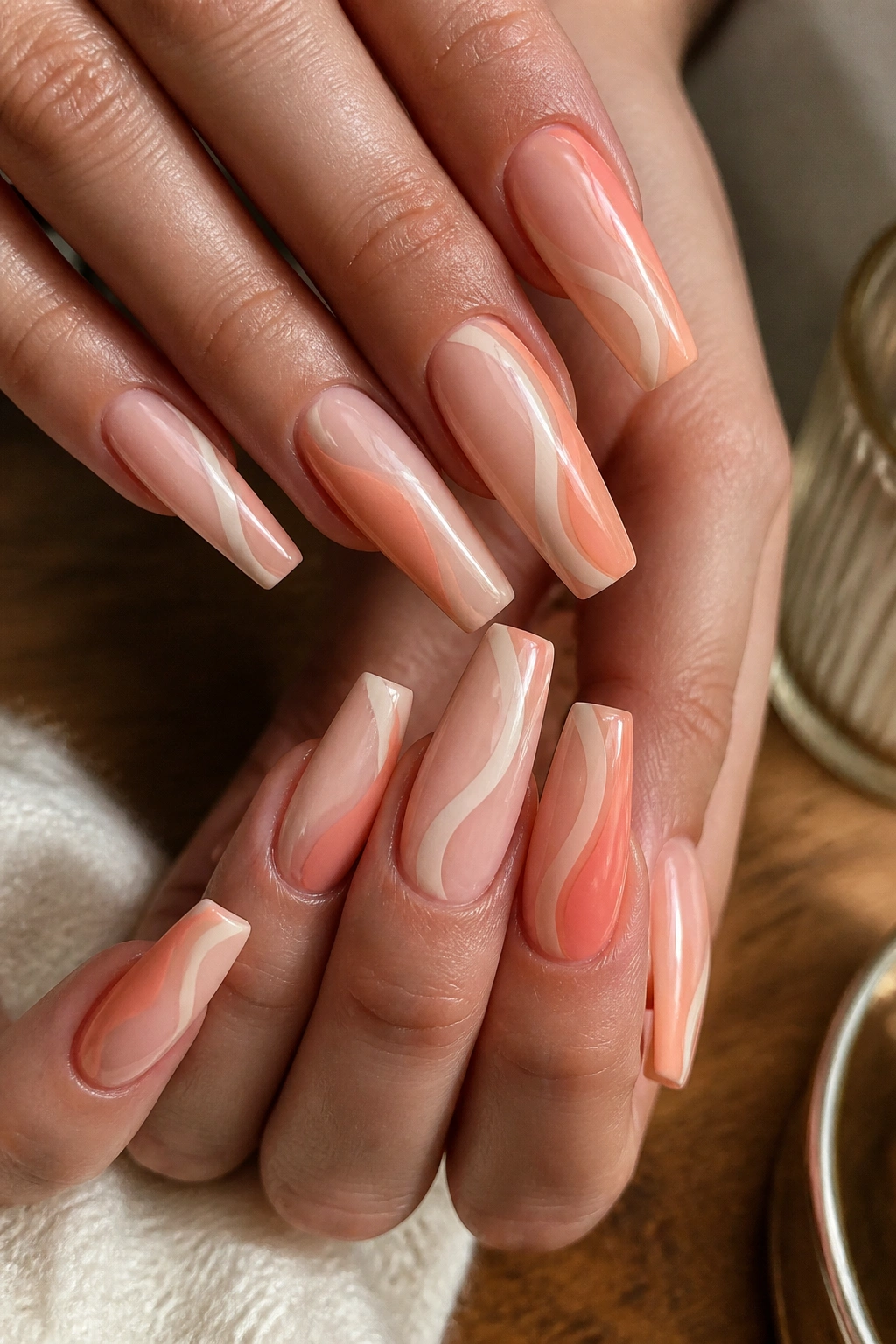 Close-up of real hands with peach sorbet side-swirl coffin nails