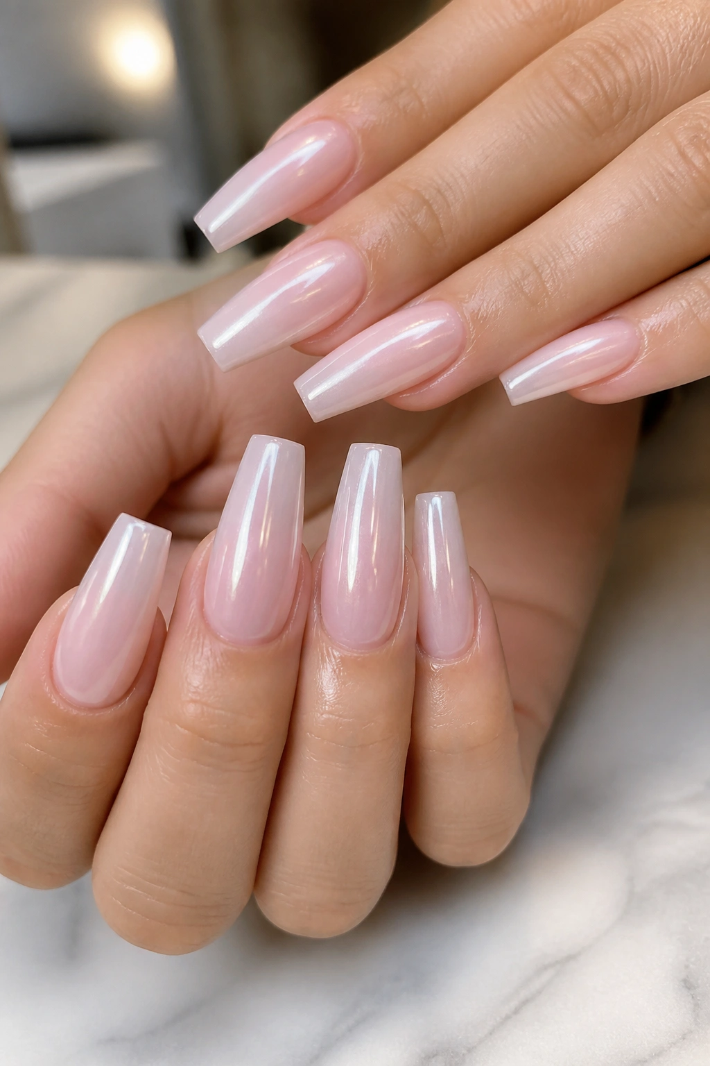 Close-up of pearl-chrome light pink coffin nails on real hands