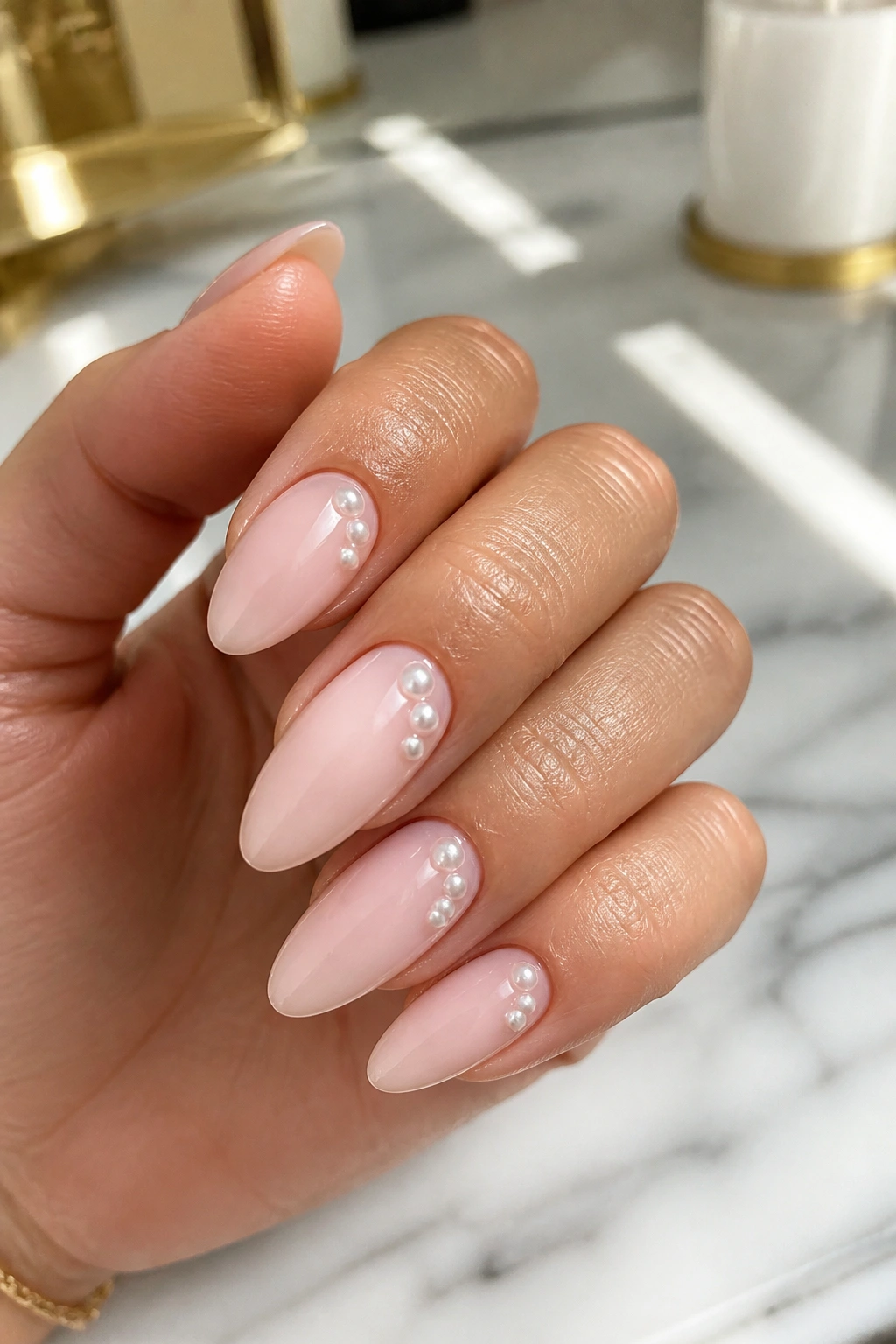 Almond nails with off-center pearl dots on pale pink base