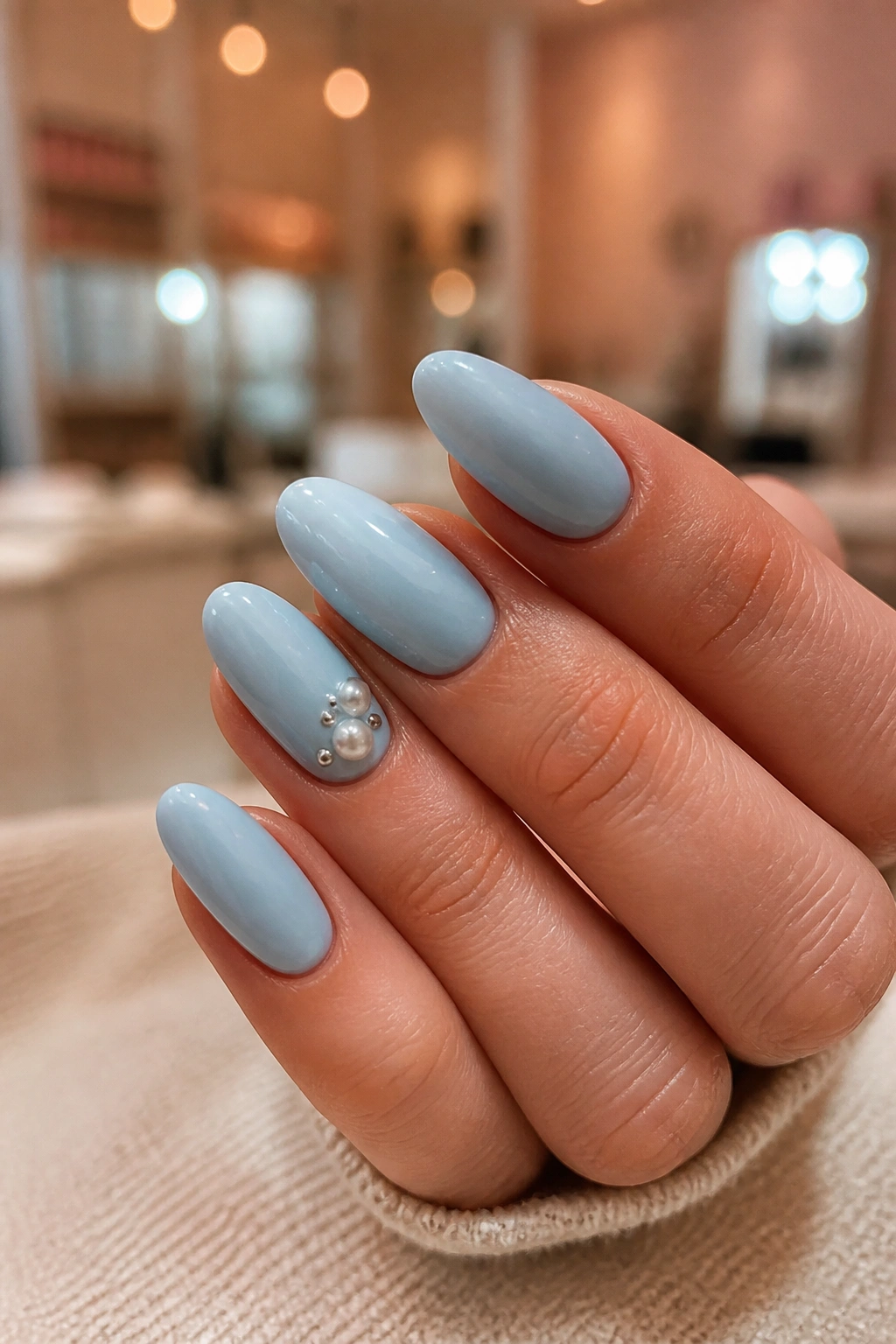 Almond nails with pearls and mini studs on a blue base