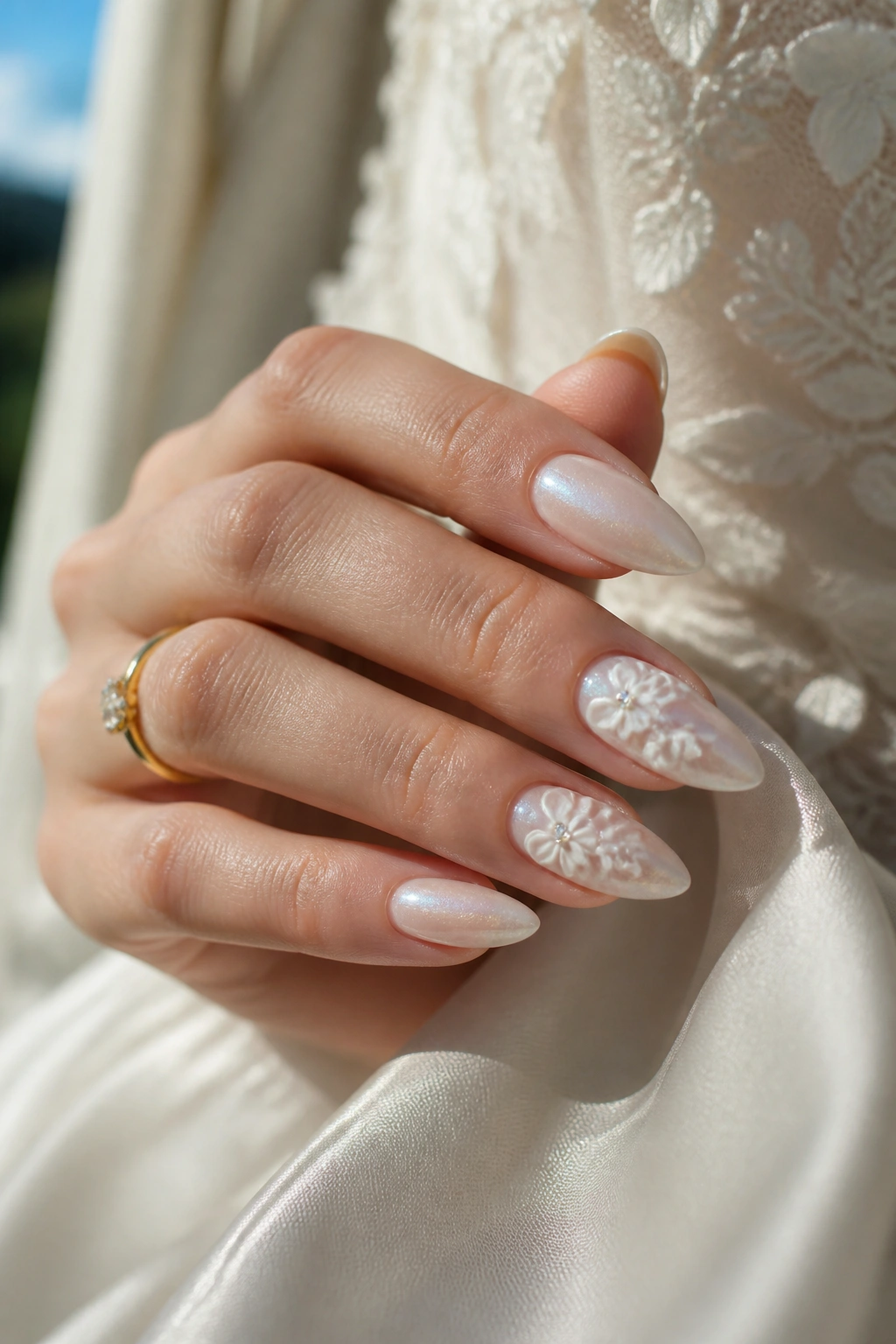 Almond nails with pearly base and ivory floral accents on a real hand in bridal mood