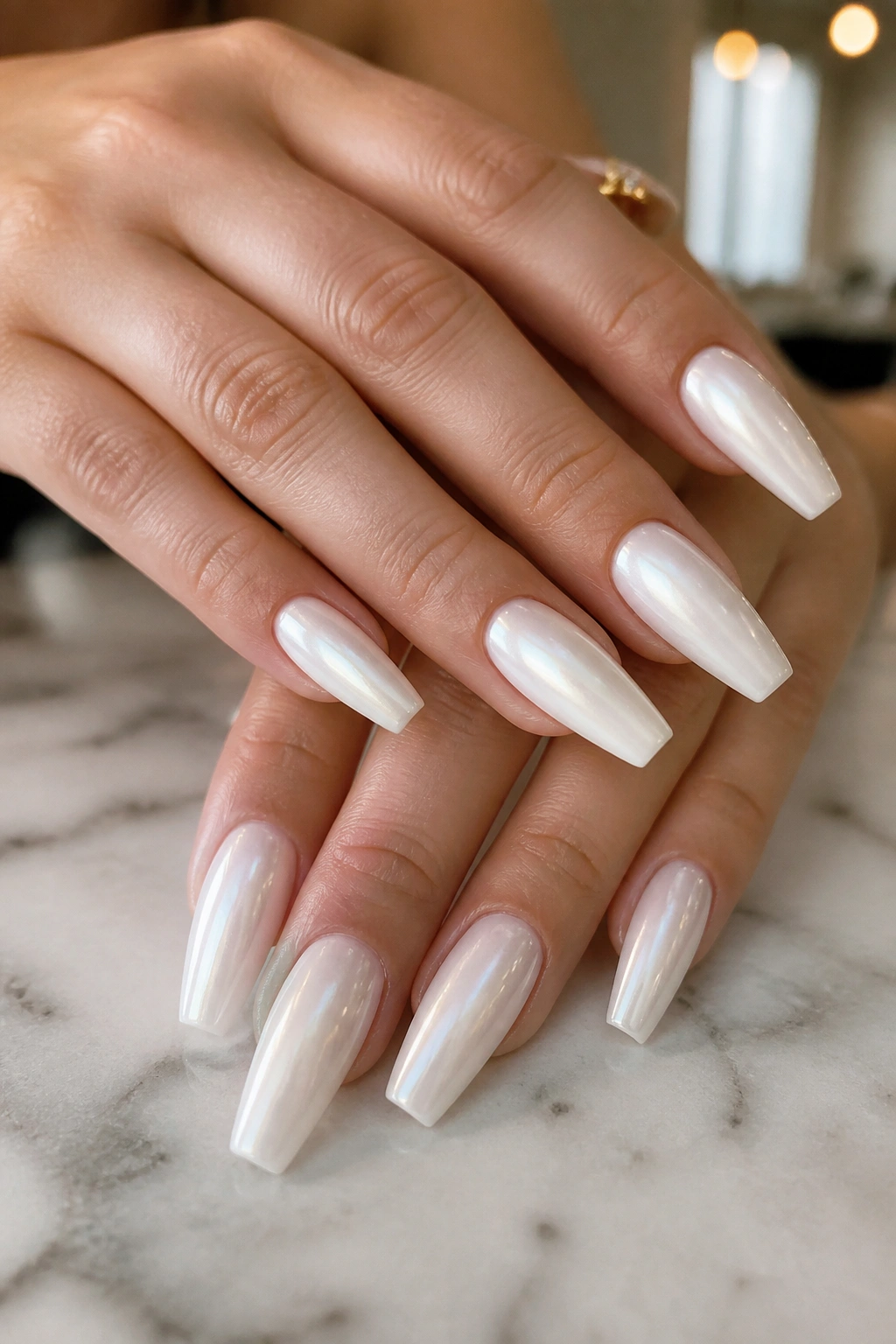 Close-up of pearly ivory coffin nails on a real hand in a softly lit salon