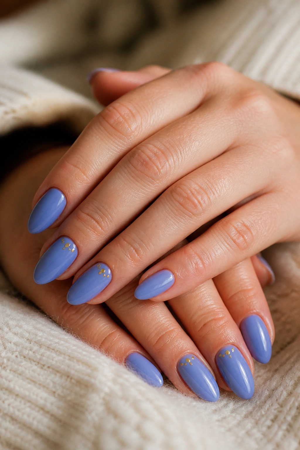 Almond nails in periwinkle with tiny gold dots in a salon setting