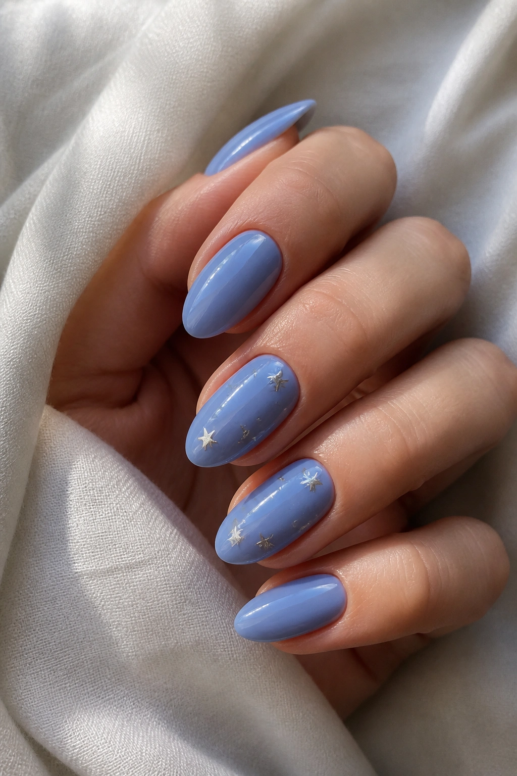 Close-up of periwinkle almond nails with subtle silver star accents