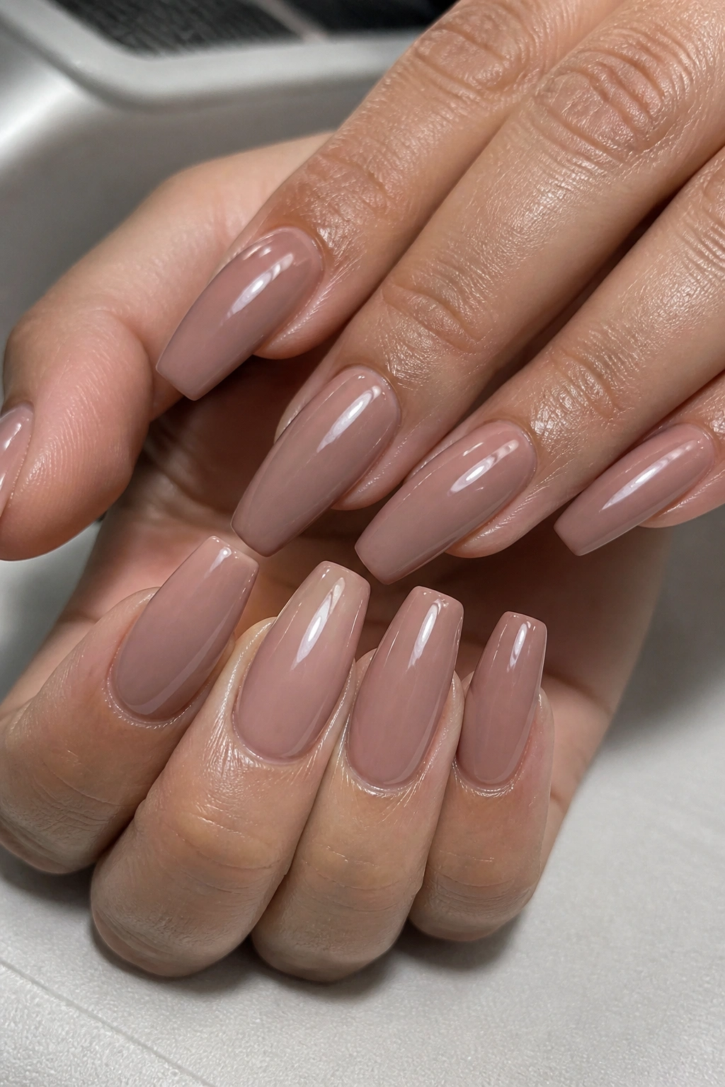 Close-up of pink-brown nude coffin nails with builder gel shine on a real hand